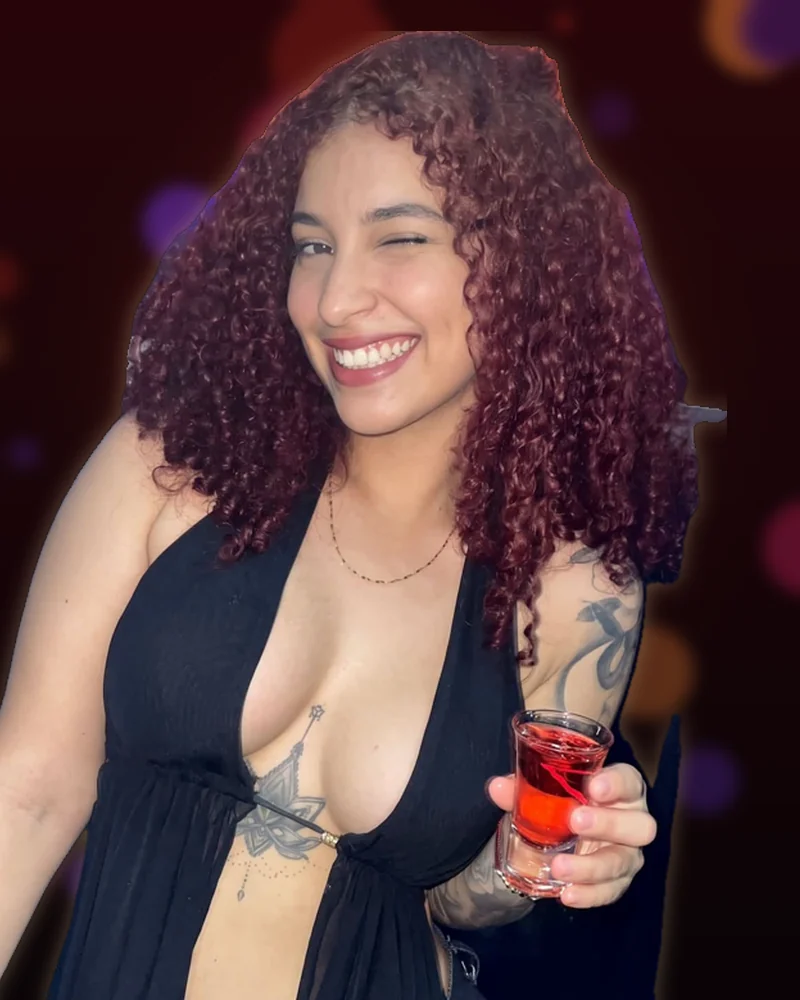 Modelo de Pegateya sonriendo con un shot en la mano, con luces de discoteca